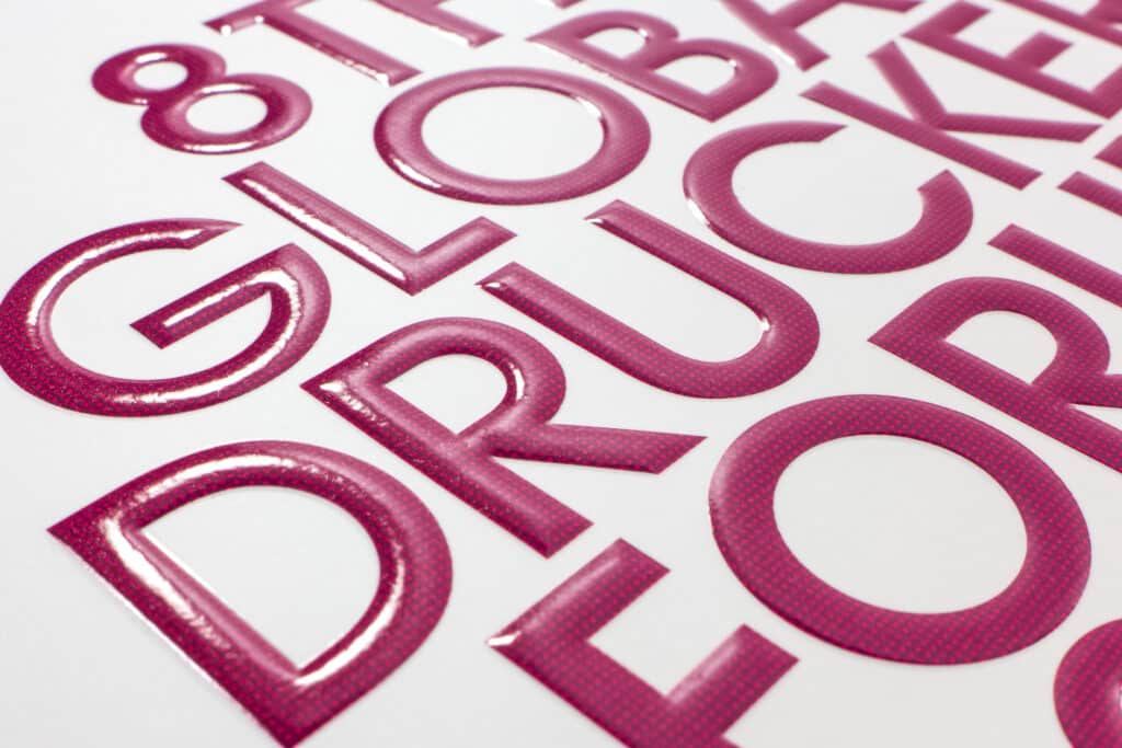 UV-Lack und Hochprägung mit ausgerundeten, herausgewölbten Buchstaben