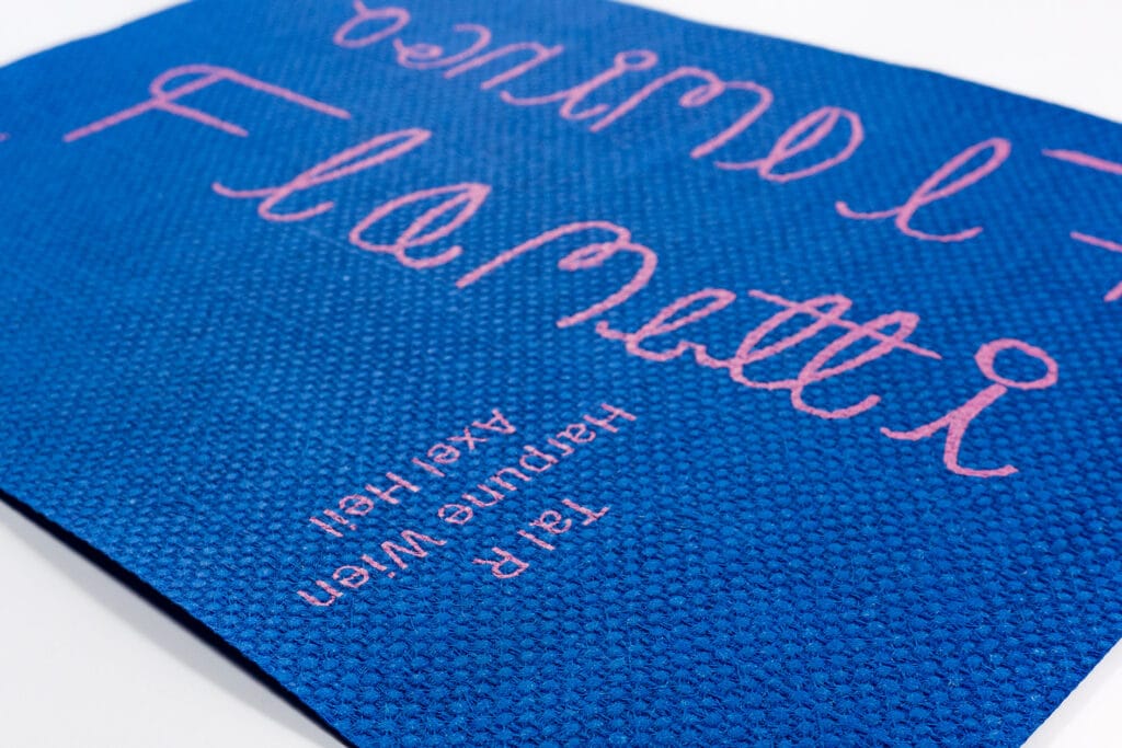 Hellrosa Druck auf dunkelblau durchgefärbtes Papier mit grober Webstruktur an der Oberfläche