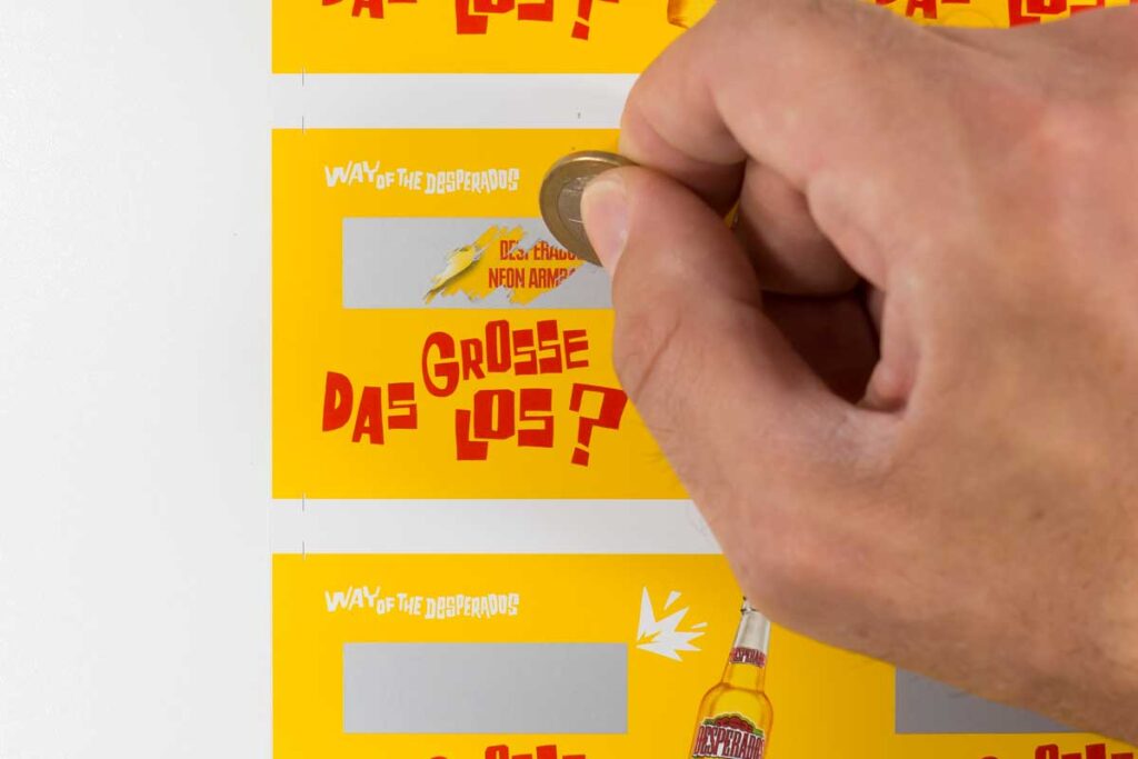 Abkratzbare Rubbelfarbe Silber auf bedrucktes Papier aufgebracht zur Abdeckung des Druckbildes eines Rubbelspiels